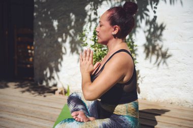 Açık havada meditasyon yapan bir kadının huzurlu manzarası. Huzurlu bir pozda oturur, farkındalığı ve rahatlığı doğayla uyum içinde kucaklar..