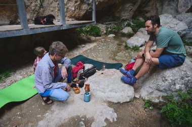 Bir grup, demleme ekipmanları ve minderlerle dolu kayalık bir bölgede kamp kurarak doğanın ortasında ortak bir bağ kurma deneyimini teşvik ediyor..