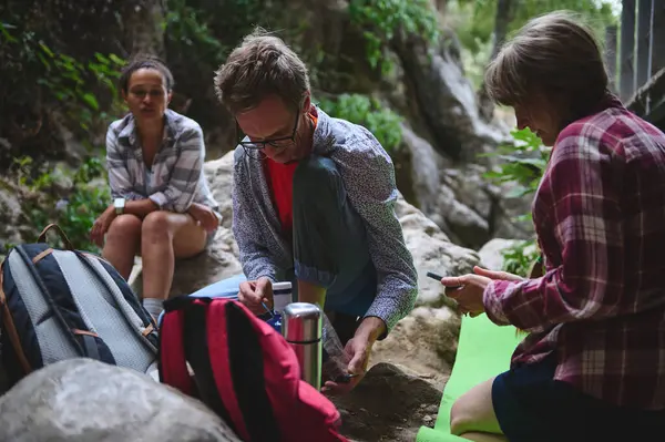 Yeşillik ve kayalarla çevrili, doğa üzerinde dinlenen bir grup arkadaş yürüyüş macerası sırasında doğa ile dostluk ve uyum sergiliyorlar..