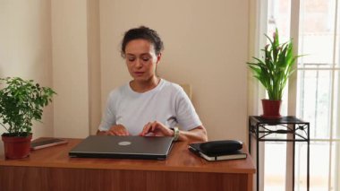 Odaklanmış kadın ofis masasında dizüstü bilgisayar açıyor. Uzaktan çalışma, verimlilik, dijital iletişim ve modern esnek kariyer yaşam tarzını yakalıyor. Çevrimiçi iş için ideal.