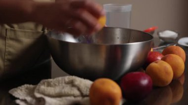 Mutfak tezgahında paslanmaz çelik bir kasede tarifini hazırlarken taze şeftalilerle ilgilenen yakın plan bir el..