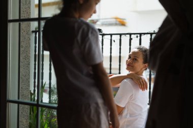 Bir anne ve çocuk balkonda birlikte vakit geçirir. Konut ortamında, doğal ışığın ve rahat atmosferin tadını çıkarırlar..