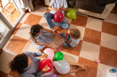 İçerde renkli balonlar hazırlarken neşeli bir aile bağı. Yaratıcılığın ve birlikteliğin neşeli anları, eğlence dolu bir aktiviteye katılan çocuklar ve yetişkinlerle yakalanır..