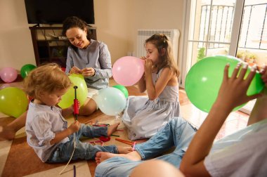 Evde neşeli bir aile buluşması, balonlarla eğlenceli anların tadını çıkarmak ve bir kutlama ortamı yaratmak. Sahnede özel bir durum sırasında sıcaklık, mutluluk ve aile birlikteliği sergileniyor..