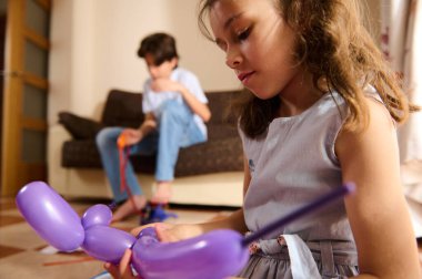 İki çocuk, sıcak ve rahat bir ortamda sanatsal yaratıcılıklarını ifade ederken evde balon modelleme faaliyetlerine girişiyor..
