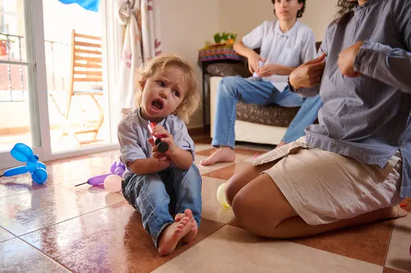 Neşeli bir çocuk güneşli bir günde evde oturur ve ailesiyle vakit geçirir. Parlak oda ve günlük ortam sıcak ve neşeli bir atmosfer yaratıyor. Aile bağları ve mutluluğu için mükemmel..