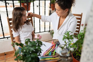 Bir anne ve küçük kızı bir bahçe masasında yaratıcı bir aktivite içindeler. Her ikisi de aile bağlarını, yaratıcılıklarını ve kişisel zamanlarını ön plana çıkaran bir anı paylaşıyorlar..