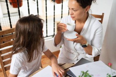 Bir anne ve kızı dışarıda biraz zaman geçiriyorlar. Anne kahveyi yudumlarken kız yaratıcı çizimler yapıyor. Birlikte, huzurlu bir ortamda ailece vakit geçirmenin tadını çıkarıyorlar..