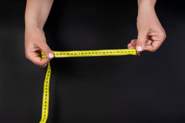 Sarı şerit ölçü koyu arkaplanda izole edilmiş ellerde