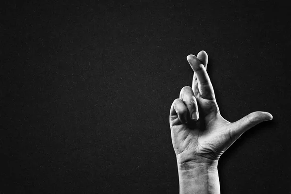 Hand with Crossed Fingers Sign in Black and White on Textured Paper Background, Copy Space