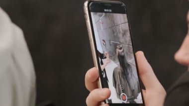 Bir kuaförün müşterinin saçını kesmesini kaydeden akıllı telefon.