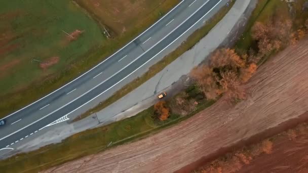 从上往下俯瞰着一条公路 公路上有汽车和一辆孤零零的公共汽车 在靠近落叶松的交叉口上 — 图库视频影像