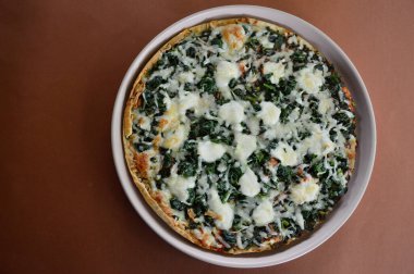 Ispanak, domates ve mozzarella içeren lezzetli vejetaryen pizza.