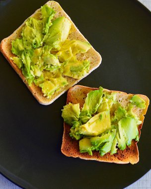 Avokado ezilmiş ve mutfakta tabakta ince tost var.