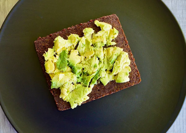 Smashed avocado and pumpernickel on a plate in the kitchen