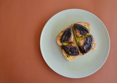 Kızarmış çoklu tahıllı ekmek, ezilmiş avokado ve ızgara portobello mantarı.