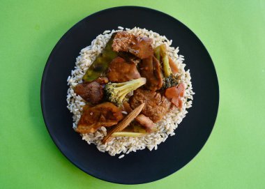 Sebzeli ay gölgesi domuz eti ve esmer yasemin pirinç yatağında servis edilir.