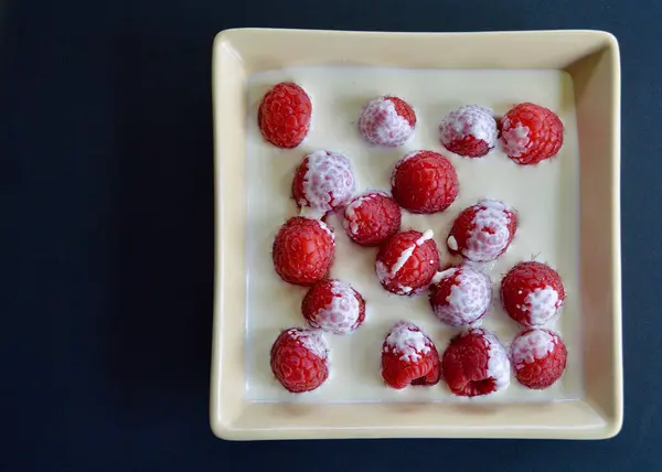 stock image raspberries and thickened cream in a dish.