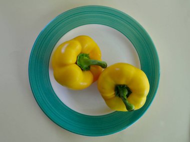 Bir tabakta iki sarı dolma biber renkli bir arka planda. 