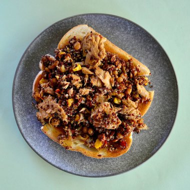 Kızarmış ekmeğin üstünde kırmızı kinoalı ton balığı salatası. 