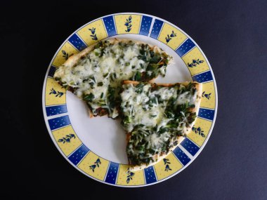 Tabakta ıspanaklı ve peynirli pizza.