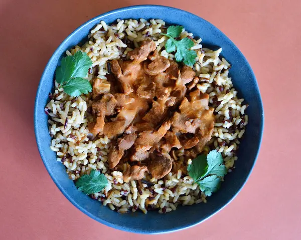 Kırmızı, kahverengi ve yabani pirinç tanelerinden oluşan bir yatakta sığır eti kebabı..