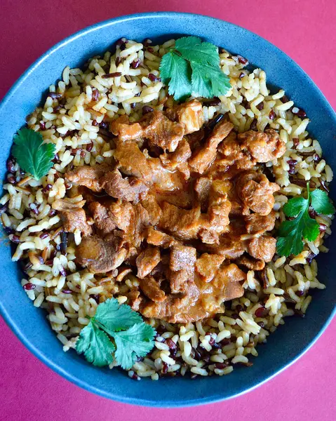 Kırmızı, kahverengi ve yabani pirinç tanelerinden oluşan bir yatakta sığır eti kebabı..