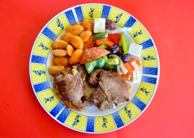 Yunan salatasıyla kuzu fileto pirzolası ve tabakta dev fasulye.