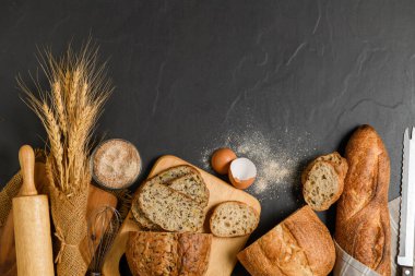 slide multi grain sourdough bread and sliced Baguette with Whole Wheat Flour on black stone background, Homemade bakery concept