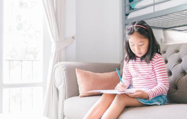 Güzel kız resim yapar ya da oturma odasındaki kanepede ödev yapar, konsepti öğrenir ve rahatlar.