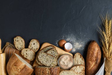 slide multi grain sourdough bread and sliced Baguette with Whole Wheat Flour on black stone background, Homemade bakery concept