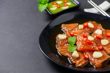 Soya soslu turşulu somon balığı ve kırmızı biberli sarımsak. Arka planda taş, Japon ve Kore yemekleri.