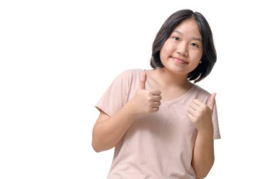 Asyalı neşeli küçük kız parmaklarını yukarı kaldırarak gülümsedi. Beyaz arka planda izole edilmesini tavsiye etti.