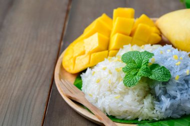 Ahşap arka planda hindistan cevizi sütü ile olgun mango yapışkan pilavı. Geleneksel Tayland Tatlısı.