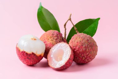 Sulu Lychee ikiye bölünmüş ve pembe arka planda izole edilmiş. Tayland meyvesi kavramı.