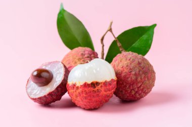 Sulu Lychee ikiye bölünmüş ve pembe arka planda izole edilmiş. Tayland meyvesi kavramı.