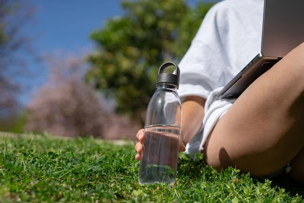 stock image freelance girl works at a laptop and holds a bottle of water aga