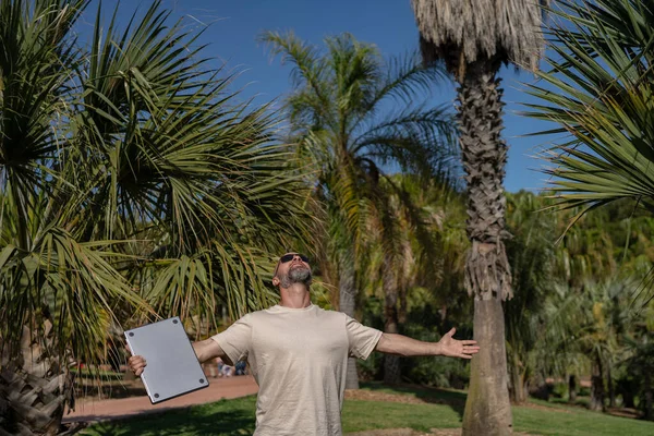 在公园里 留着胡子的男性自由职业者手里拿着笔记本电脑 — 图库照片