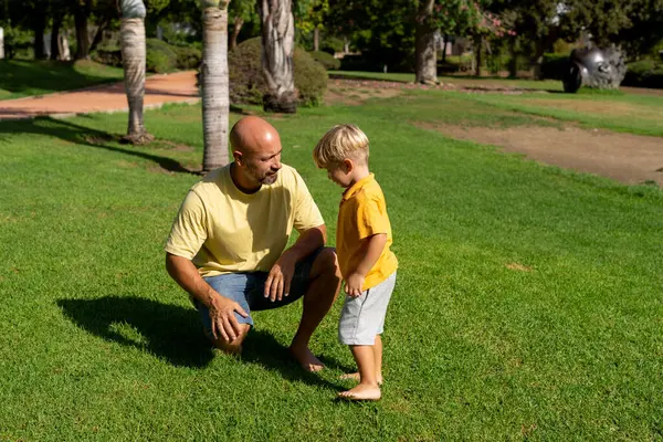 Little boy hugs his father and explains something to him, father listens carefully and smiles, son and father spend time together, talk, walk in the park