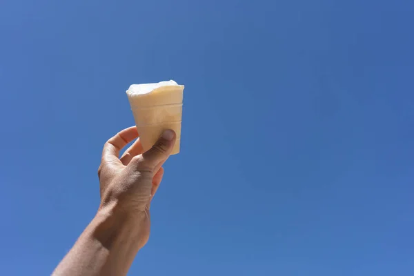 ice cream in a cup in hand against the sky