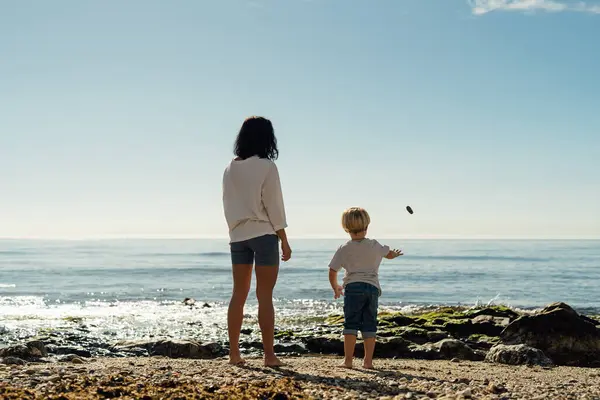 mother and son throw stones into the sea. family walk by the sea.family values