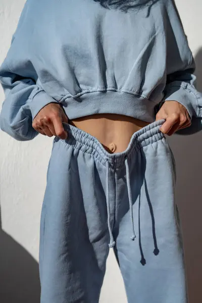 Athletic girl in a blue tracksuit. Fitness woman in a blue sports suit. fitness model. Sport style. A model poses in a tracksuit. Close-up details of the body of a girl in a tracksuit