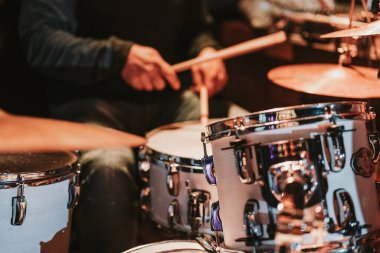 Musician playing the drums during a concert, no faces shown, shallow depth of field