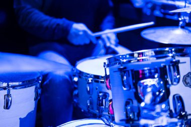 Musician playing the drums during a concert, no faces shown, shallow depth of field