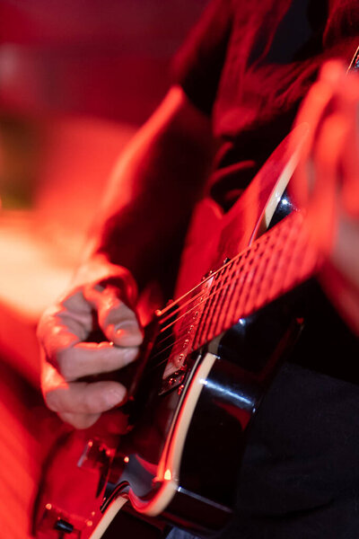 Close up of a musician playing the electric guitar during a concert, no faces are shown, shallow depth of field, vertical image