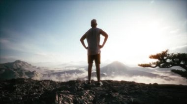 Başarı kavramı. Gün batımında bir dağın tepesinde duran adam. Adam ellerini kaldırır, bir dağın tepesinde durur. Dağın tepesinde duran genç adam. 3d görselleştirme