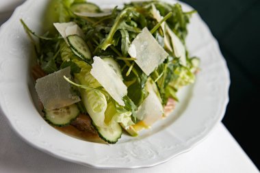 Ançüezli sezar salatası ve masada beyaz bir tabakta parmesan.