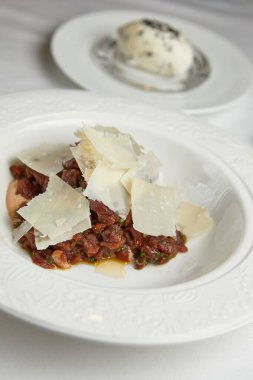 Restoranda beyaz bir tabakta parmesan peyniri ile marine edilmiş balık katranı.