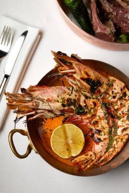 Tatlı ve ekşi soslu karides ve limon. Bakır bir tabakta, restorandaki bir masada.