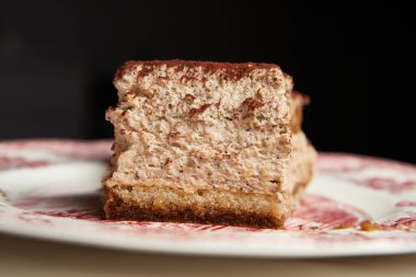 Tiramisu, siyah arka planda güzel bir tabakta yakın plan.